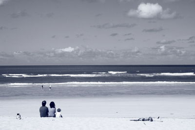 Family relaxing at beach against sky