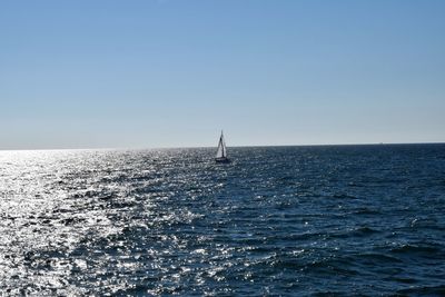 Sailboat sailing in sea against clear sky