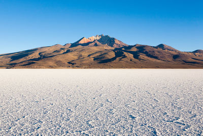 Scenic view of desert against clear blue sky