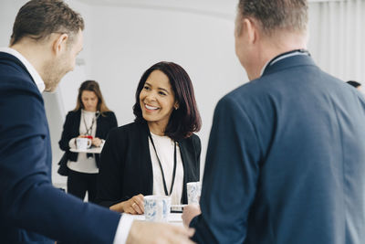 Happy female entrepreneur discussing with male colleagues in office seminar