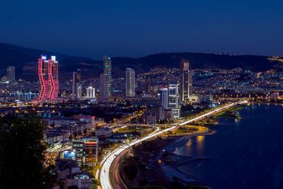 Illuminated city by buildings against clear sky at night