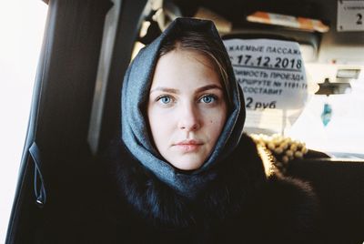 Portrait of beautiful young woman wearing scarf sitting in car