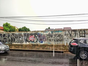 Graffiti on wall by road against sky