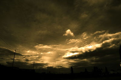 Silhouette of trees against cloudy sky