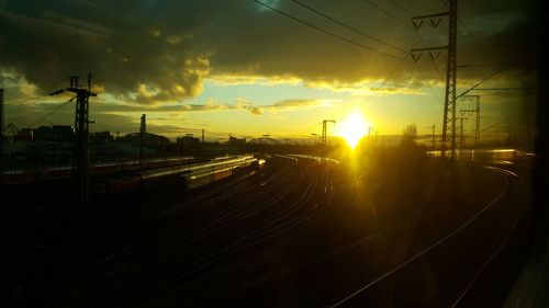 Silhouette railway tracks against sky during sunset