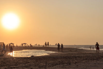 Silhouette people on beach against sky during sunset