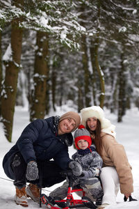 Full length of woman sitting on snow covered field