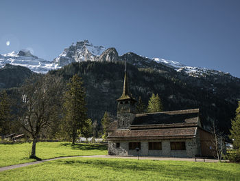 Beautiful old rustic alpine church and snow capped alpine mountains.
