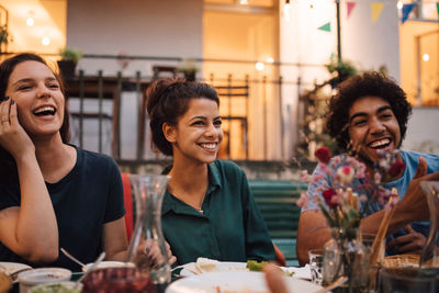 Happy young friends enjoying dinner party in backyard