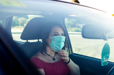 View of woman wearing flu mask sitting in car