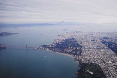 Aerial view of city by river against sky