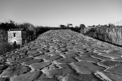 Cobblestone street amidst old buildings against clear sky