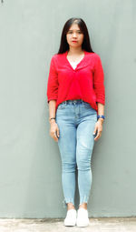 Portrait of young woman standing against wall