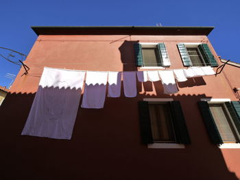 Low angle view of clothes drying on building against clear sky