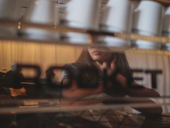 Young woman reflecting on glass in cafe