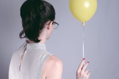 Midsection of woman holding balloons against gray background