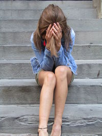 Full length of woman sitting against wall