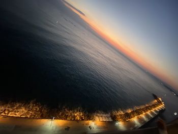 High angle view of illuminated sea against sky at sunset
