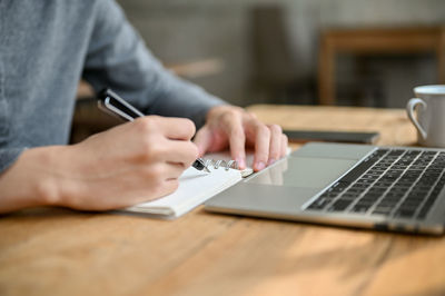 Midsection of man using laptop on table