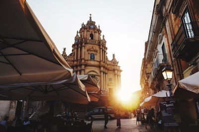 People on street by cathedral and buildings in city