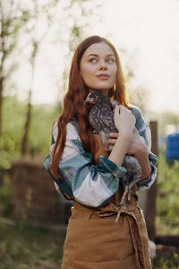 Portrait of young woman standing against trees