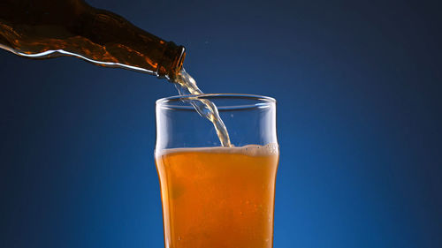 Close-up of beer glass against blue background