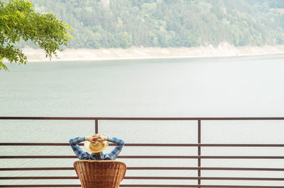 Wicker chair by sea against trees