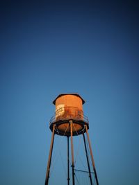 Low angle view of water tower against clear blue sky