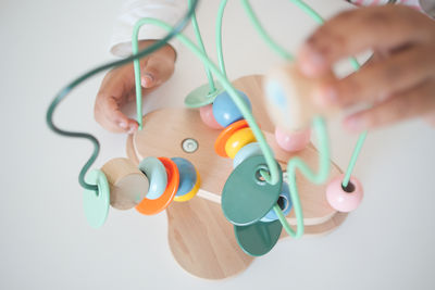 Cropped hand of woman holding in-ear headphones against white background