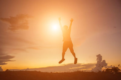 Silhouette man jumping against sky during sunset