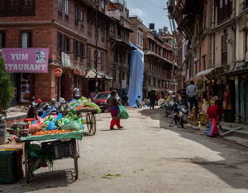 People walking on street amidst buildings in city