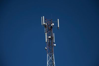 Low angle view of communications tower against blue sky