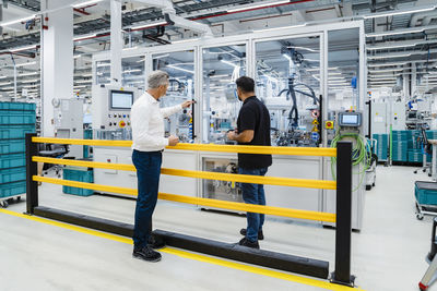 Businessman pointing at machine with engineer in factory