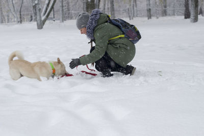 Woman playing with dog on snow covered field