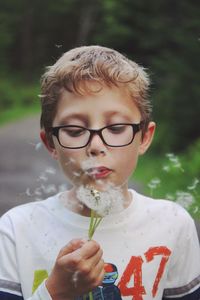 Close-up of boy blowing dandelion