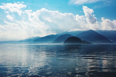 Scenic view of sea by mountains against sky