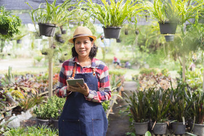 Portrait of smiling young woman standing against plants