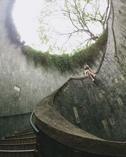 Low angle view of woman sitting on railing