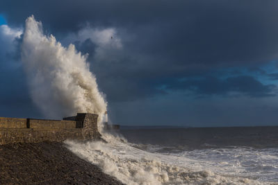 Waves splashing on shore against sky