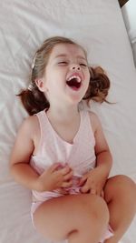Cute baby girl lying on bed at home