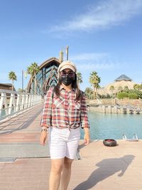 Low angle view of a lady standing by sea against sky