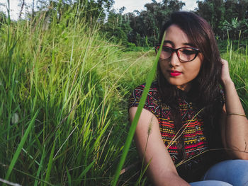 Beautiful young woman sitting amidst grass