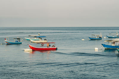 Fishing boats moored in sea against clear sky