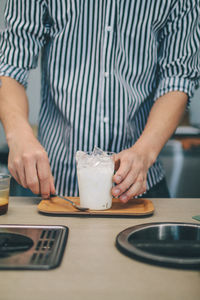 Midsection of man holding drink on table