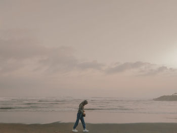 Full length of woman walking on beach against sky