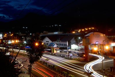 Light trails on road in city against sky at night