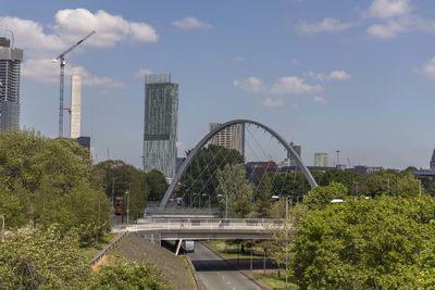 Bridge by buildings against sky in city