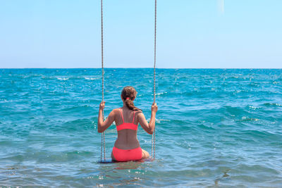 Rear view of woman in sea against clear sky