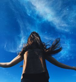 Low angle view of woman against blue sky