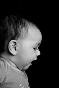 Close-up of baby girl against black background